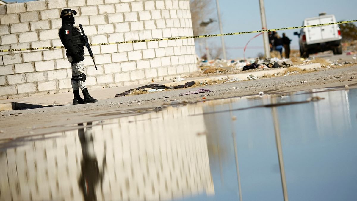 A member of the Mexican National Guard keeps watch at the scene where unknown assailants left the body of a decapitated person, in Ciudad Juarez. Credit: Reuters Photo