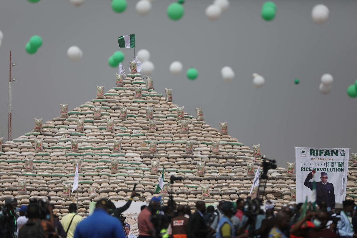 People gather to see rice pyramids at the launch of the largest rice pyramids in Abuja, Nigeria, on January 18, 2022. - The bags of rice which were planted and harvested by Rice Farmers Association of Nigeria (RIFAN) from states in Nigeria, are one million rice paddies stacked in 15 separate pyramids which is expected to solve the food crisis in Nigeria. Credit: AFP Photo