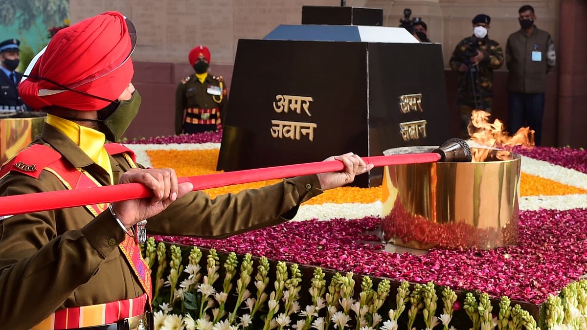A torch being lit from Amar Jawan Jyoti flame to be taken to National War Memorial for merging it with the flame at the Memorial, in New Delhi. Credit: PTI Photo