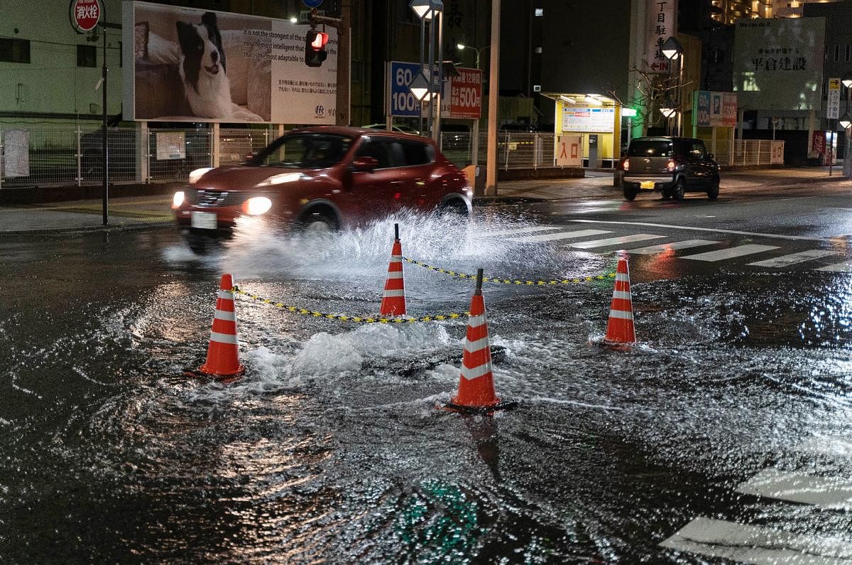 Water flowing from a manhole floods an intersection in Oita early on January 22, 2022, after a 6.4-magnitude earthquake struck off the Pacific coast in southwestern Japan. Credit: AFP Photo