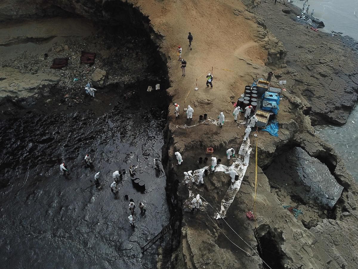 Aereal view of cleaning crews working to remove oil from a beach annexed to the summer resort town of Ancon, northern Lima, on January 22, 2022 after a spill which occurred during the offloading process of the Italian-flagged tanker