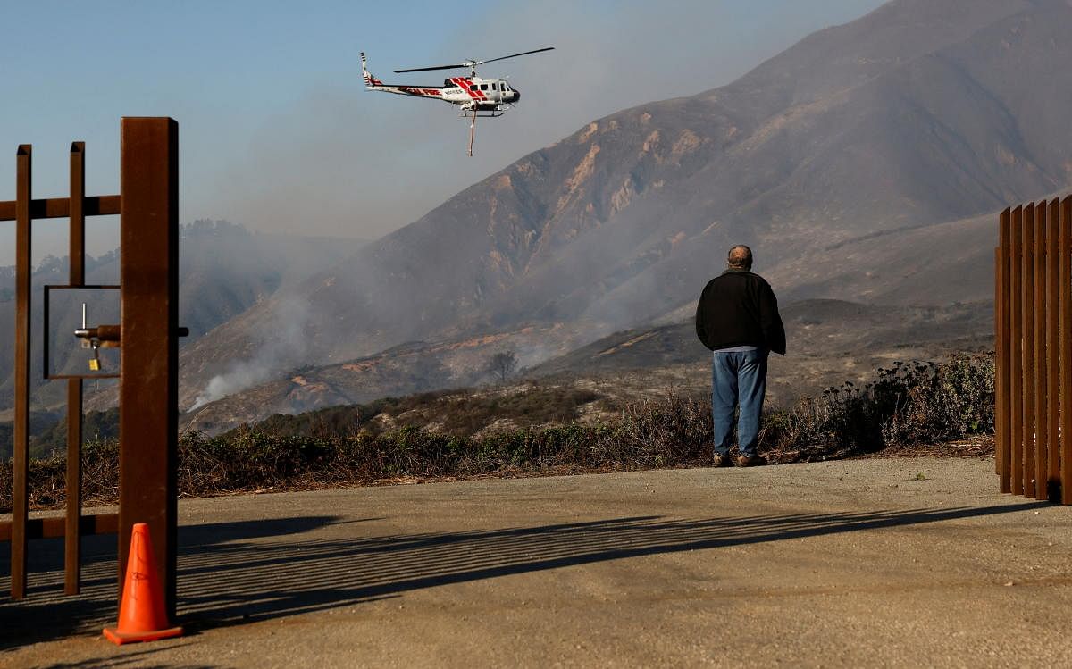 A local resident looks on as a Cal fire water dropping helicopter flies by while the Colorado fire burns near Big Sur, California. Credit: Reuters Photo