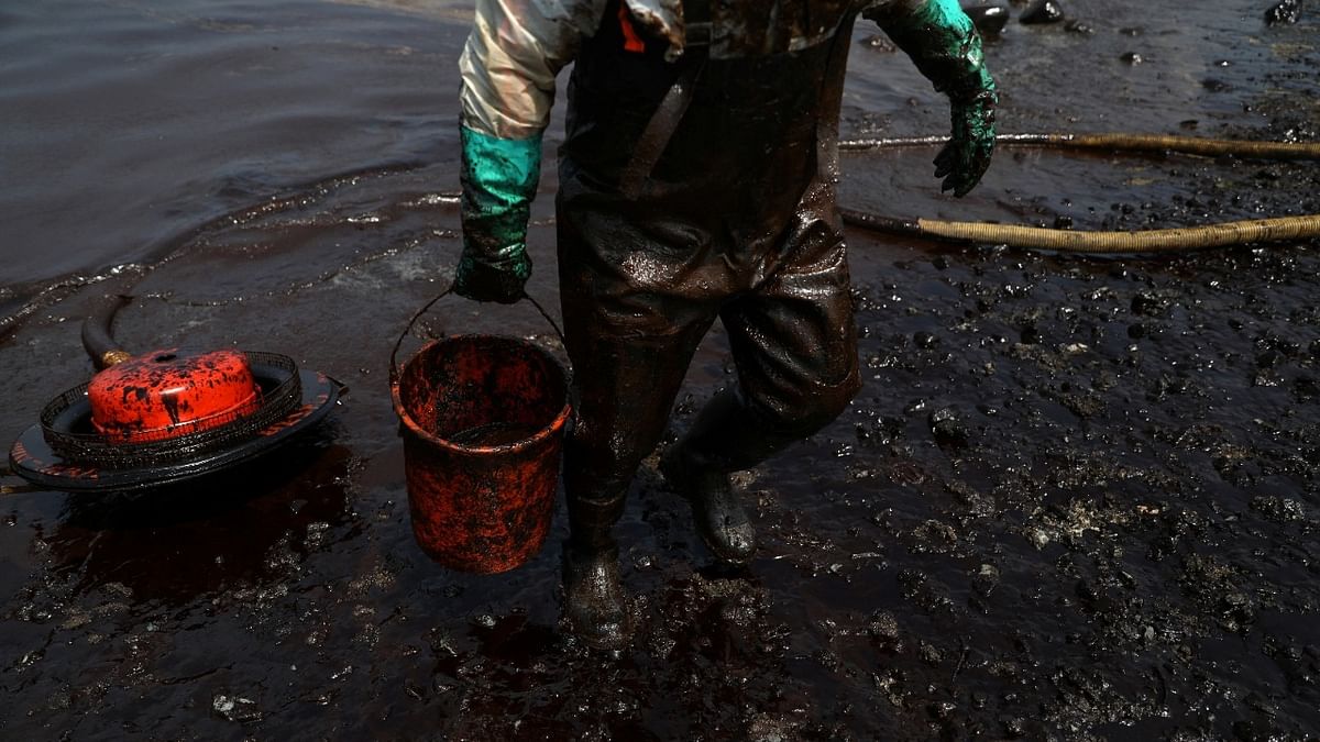 A worker cleans up an oil spill following an underwater volcanic eruption in Tonga, in Ancon. Credit: Reuters Photo