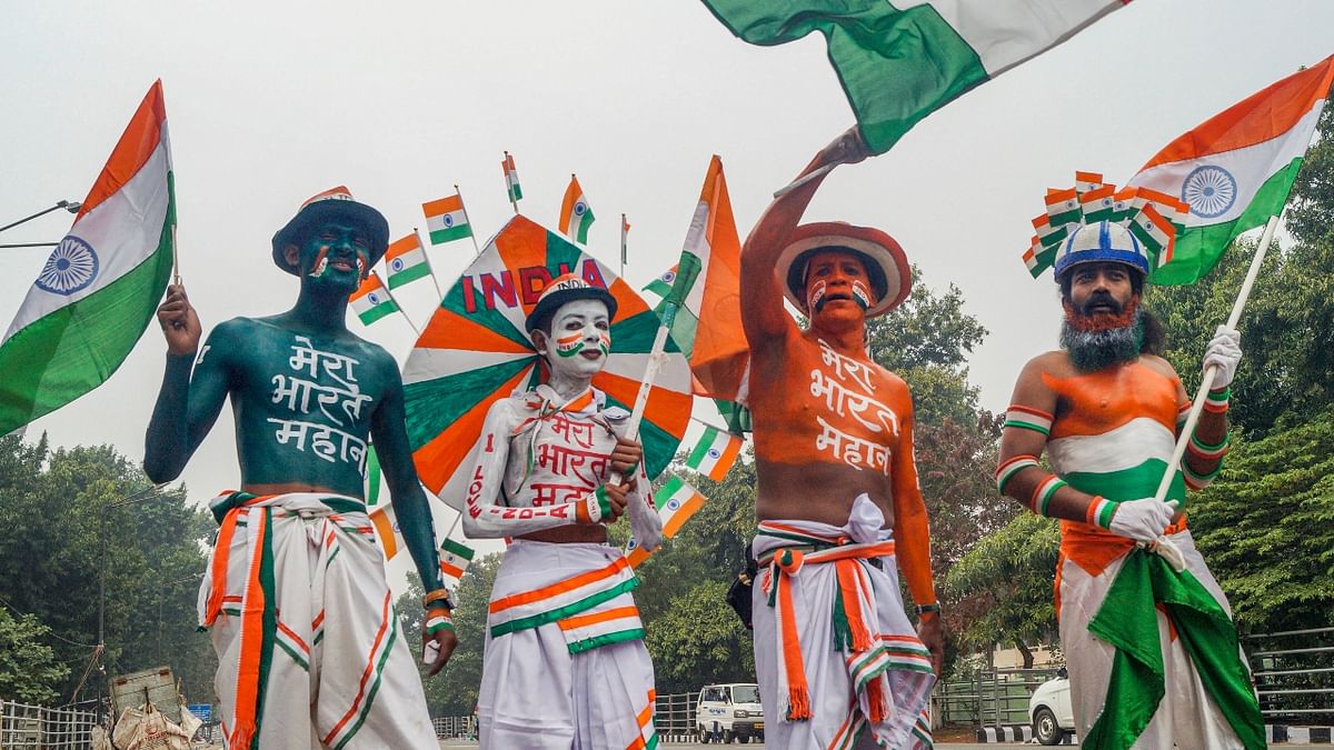 Volunteers with their body painted in tricolor hold national flags as they perform a street play on the eve of Republic Day 2022 in Bhubaneswar. Credit: PTI Photo