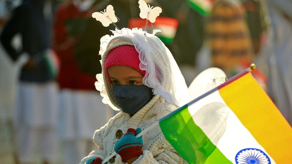 A girl wearing a face mask holds the Indian national flag as she attends a flag hoisting ceremony during India's Republic Day celebrations in Ahmedabad. Credit: PTI Photo
