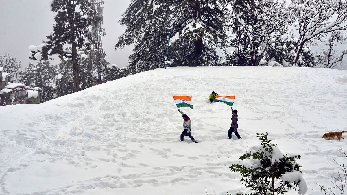 Youngsters holding the national flag walk on snow-covered hill on the eve of the Republic Day in Shimla. Credit: PTI Photo