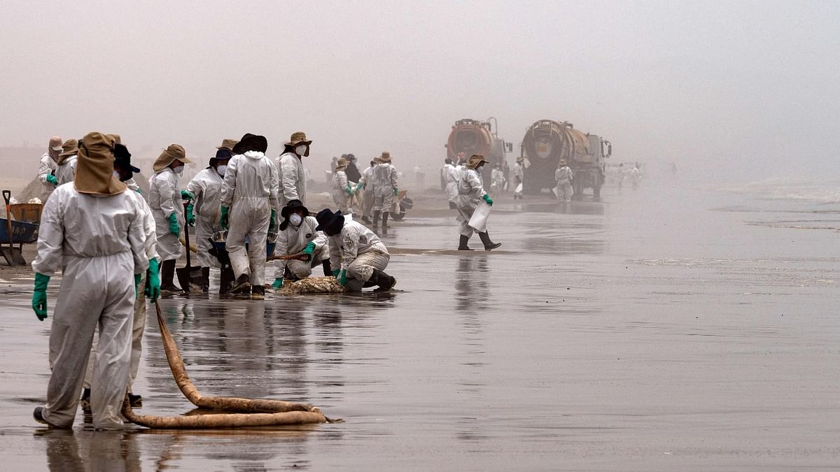 Cleaning crews work to remove oil from the Cavero Beach in Callao, Peru, on January 26, 2022, after a spill occurred during the offloading process of the Italian-flagged tanker