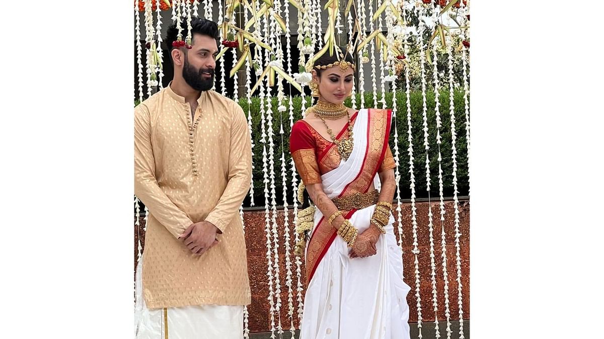 Mouni is seen in a red-and-white saree, while Nambiar is dressed in a biege kurta and dhoti. Credit: Special Arrangement