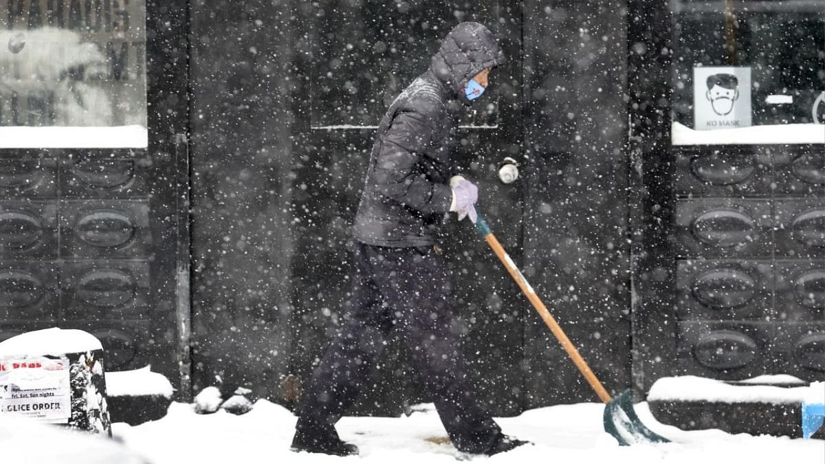 A worker clears snow from the front of a business on February 02, 2022 in Chicago, Illinois. Credit: AFP Photo