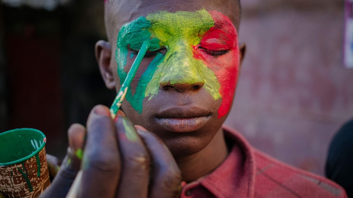 A supporter of Senegal national football team gets his face painted in Dakar. Credit: AFP Photo
