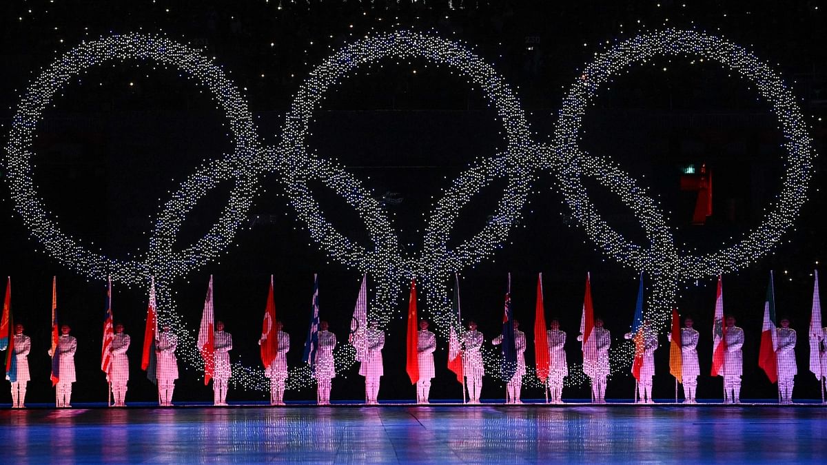 Volunteers hold the flags of participating countries below the Olympic rings during the closing ceremony of the Beijing 2022 Winter Olympic Games in Beijing. Credit: AFP Photo