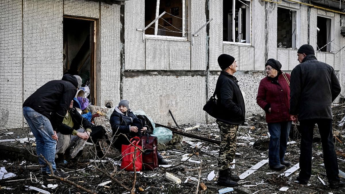 People stand outside a destroyed building after heavy bombings on the eastern Ukraine town of Chuguiv on February 24, 2022. Credit: AFP Photo