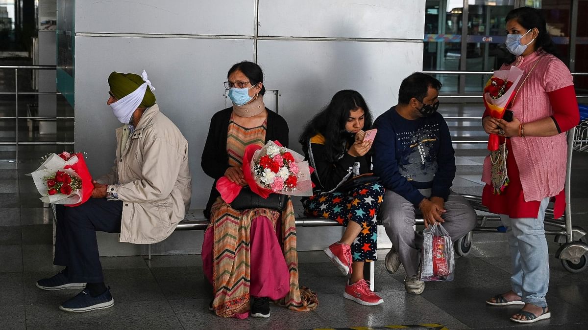 Relatives of students evacuated from Ukraine in a special flight wait with flowers for their arrival outside the Indira Gandhi International Airport in New Delhi. Credit: AFP Photo