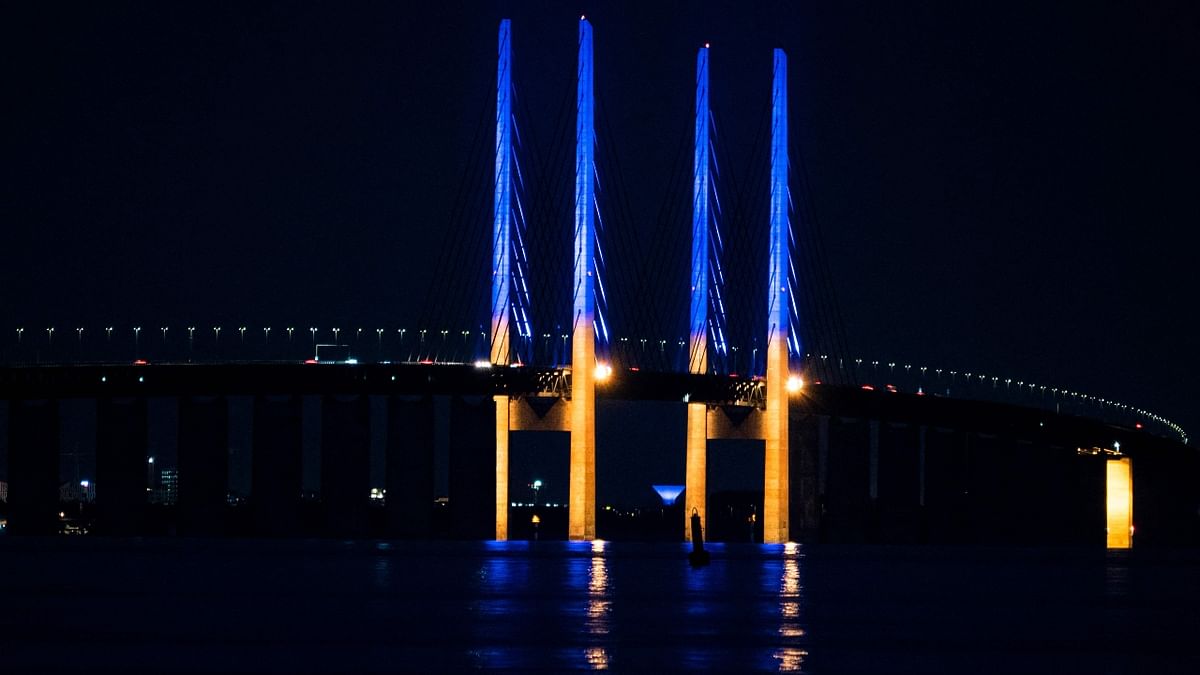 The 200-meter-high pylons on the Oresund Bridge, between Denmark and Sweden, light up in yellow and blue, in support of Ukraine, seen from Copenhagen. Credit: AFP Photo