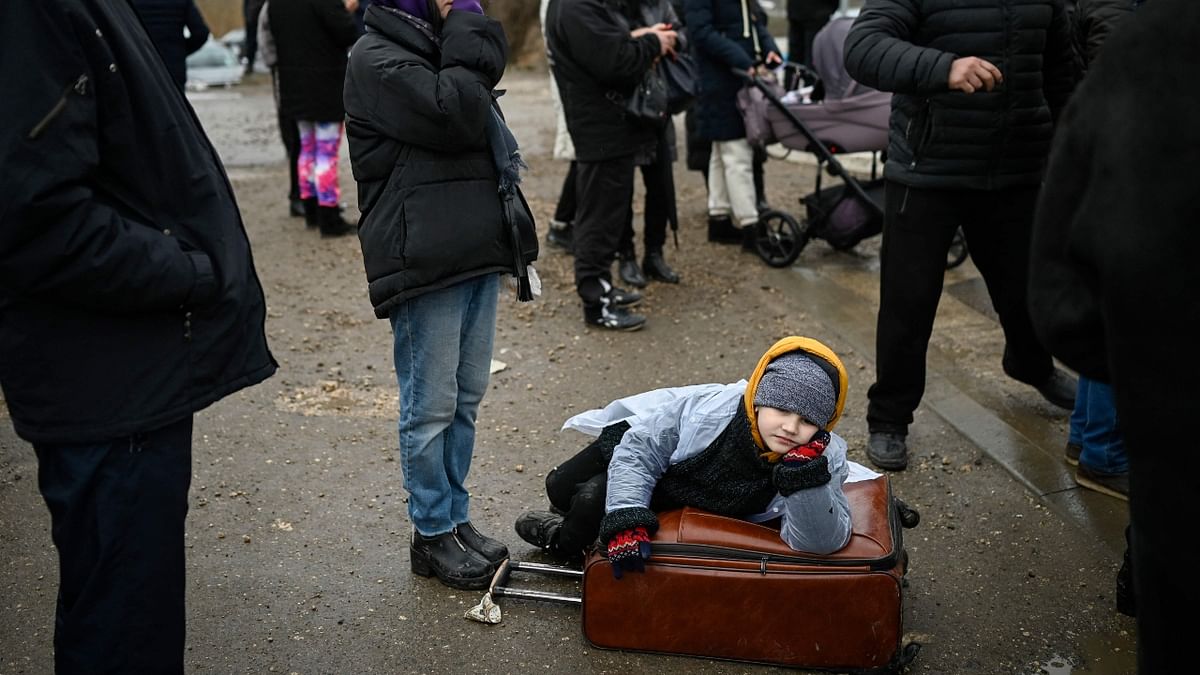 A child rests on a suitcase after crossing the Moldova-Ukraine border checkpoint near the town of Palanca. Credit: AFP Photo