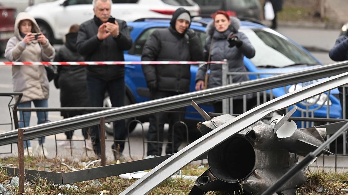 People click photos of the remains of a shell standing behind the cordoned off area in Kyiv. Credit: AFP Photo