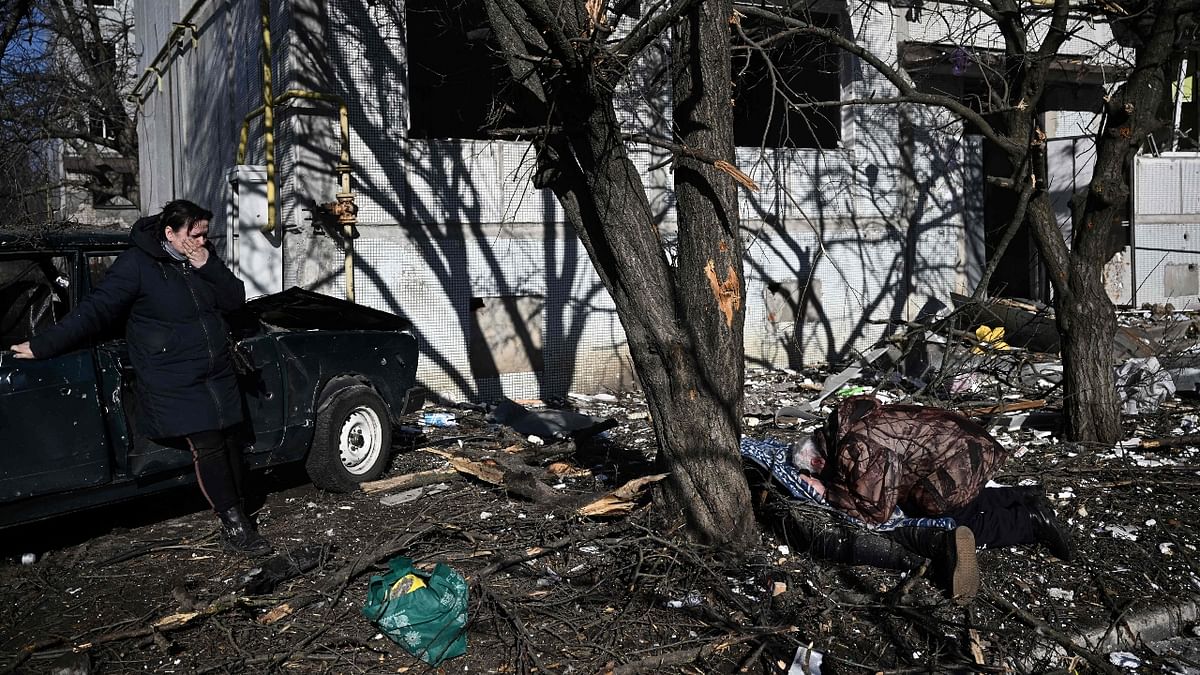 People react beside the body of a relative outside a destroyed building after bombings on the eastern Ukraine town of Chuguiv. Credit: AFP Photo