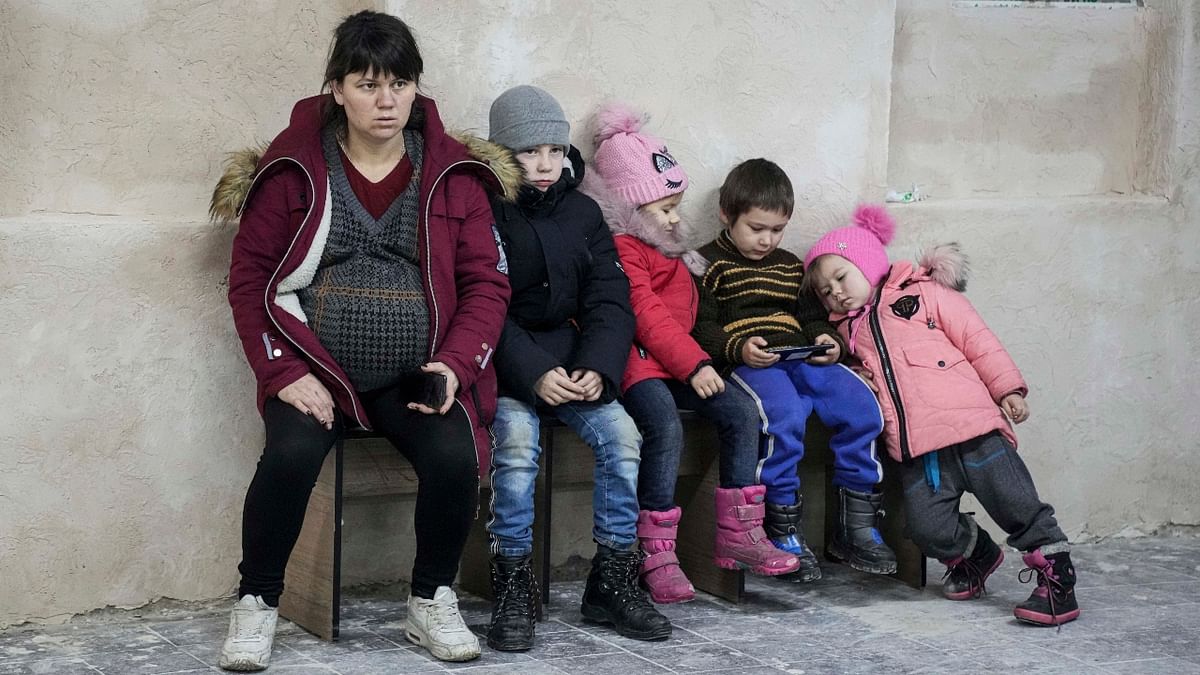 A pregnant woman and children sit on a bench in the improvised bomb shelter in a sports center in Mariupol, Ukraine. Credit: AP Photo