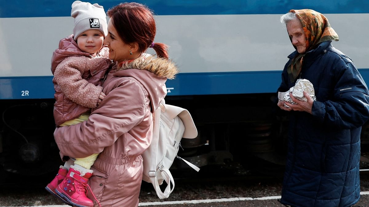 Women and a child fleeing Russia's invasion of Ukraine walk next to a train in Zahony, Hungary. Credit: Reuters Photo