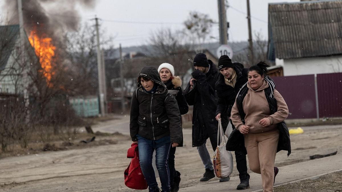 Local residents look for cover as they escape from the town of Irpin after heavy shelling from the Russian troops. Credit: Reuters Photo