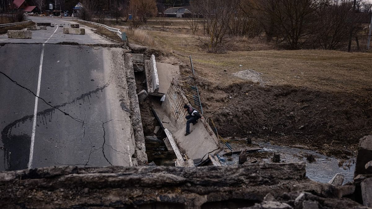 A civilian crosses a blown-up bridge in Ukraine. Credit: AFP Photo