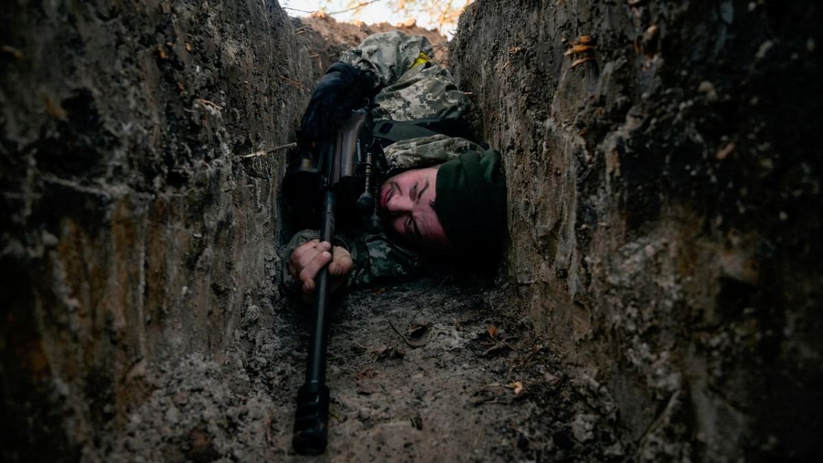 A Ukrainian soldier hides from a helicopter airstrike amid Russia's invasion of Ukraine, near Demydiv. Credit: Reuters photo
