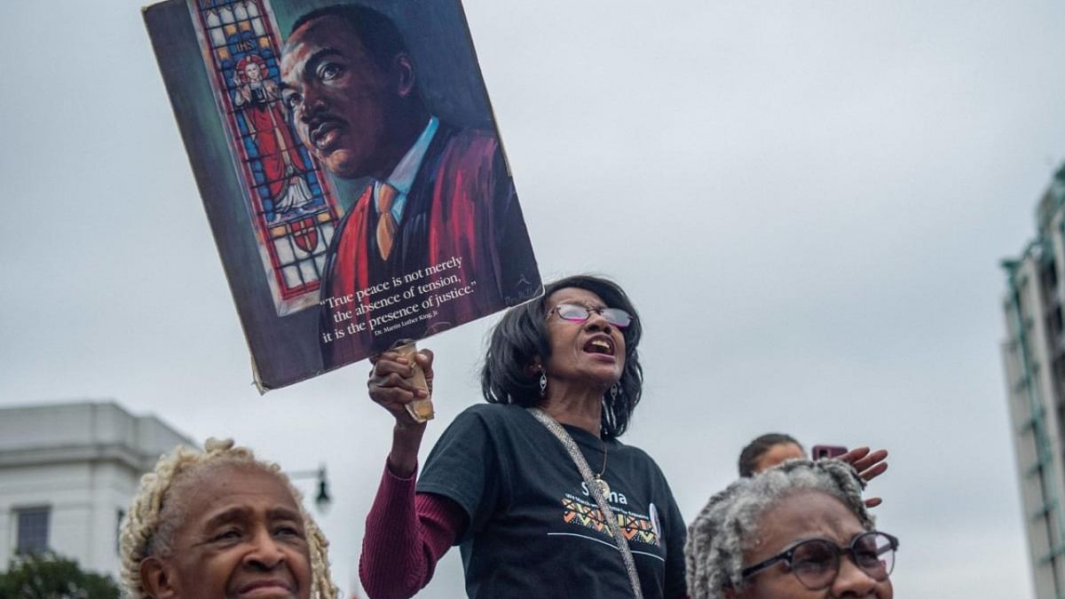 A supporter hold a sign of the late Martin Luther King Jr. while listening during a rally at the Alabama State Capitol on March 11, 2022 in Montgomery, Alabama. Credit: AFP Photo