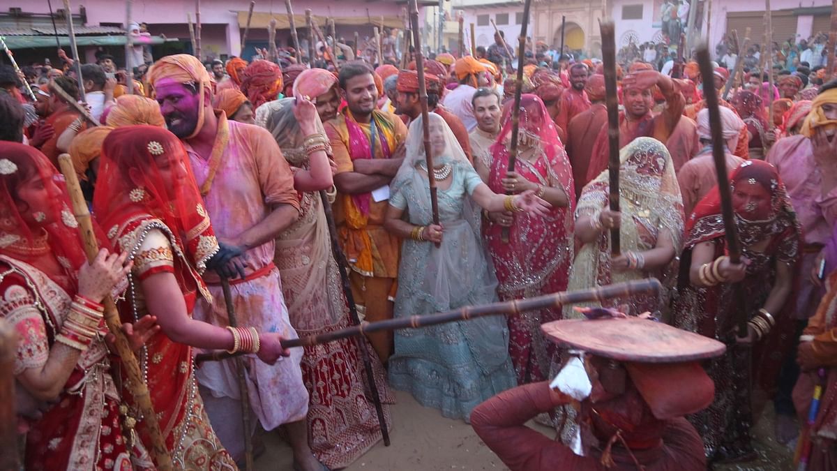 In the festival, men try to smear women with colour, who traditionally protect themselves with lathis or sticks. Credit: PTI Photo