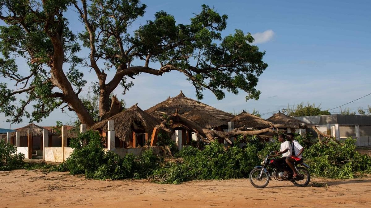 Men drive on motorcycle past a destroyed house following the passage of cylone Gombe in Nampula. Credit: AFP Photo