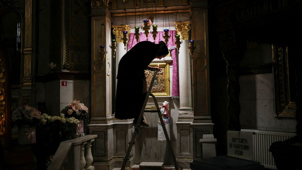 A woman climbs down a stepladder after she lit candles inside an Orthodox church, as Russia's invasion of Ukraine continues, in downtown Odessa. Credit: Reuters Photo