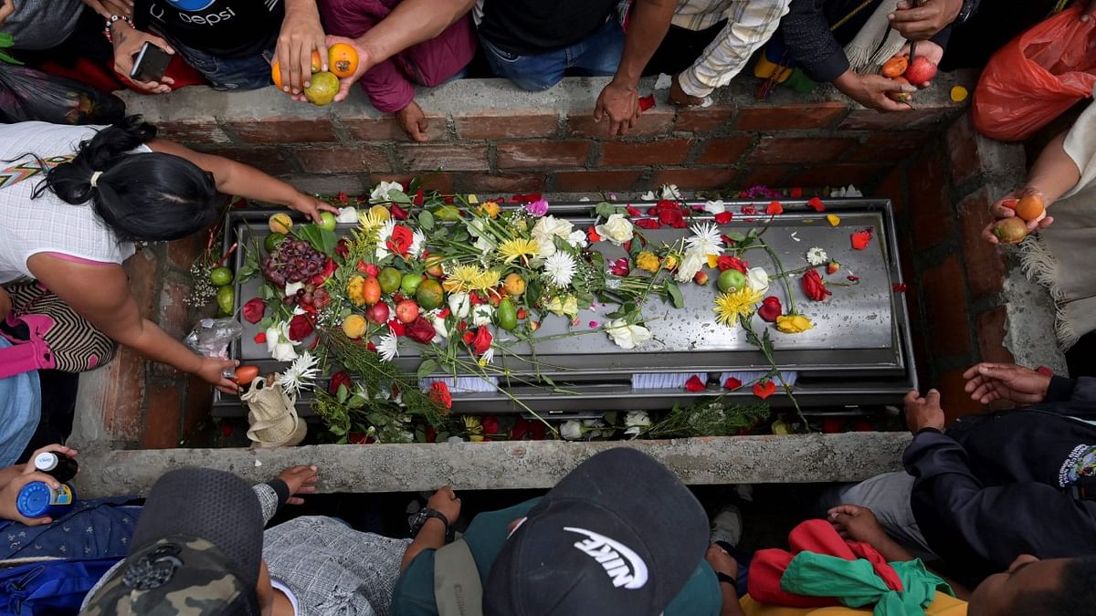 A colombian indigenous puts fruit over the coffin of indigenous authority Jose Miller Correa, killed on Monday in a highway near Popayan, by an illegal armed group in Damina, rural area of Toribio. Credit: AFP Photo