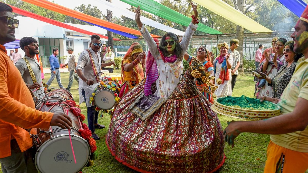 Daubed in colours, a guest dances her heart out on dhol beats. Credit: PTI Photo