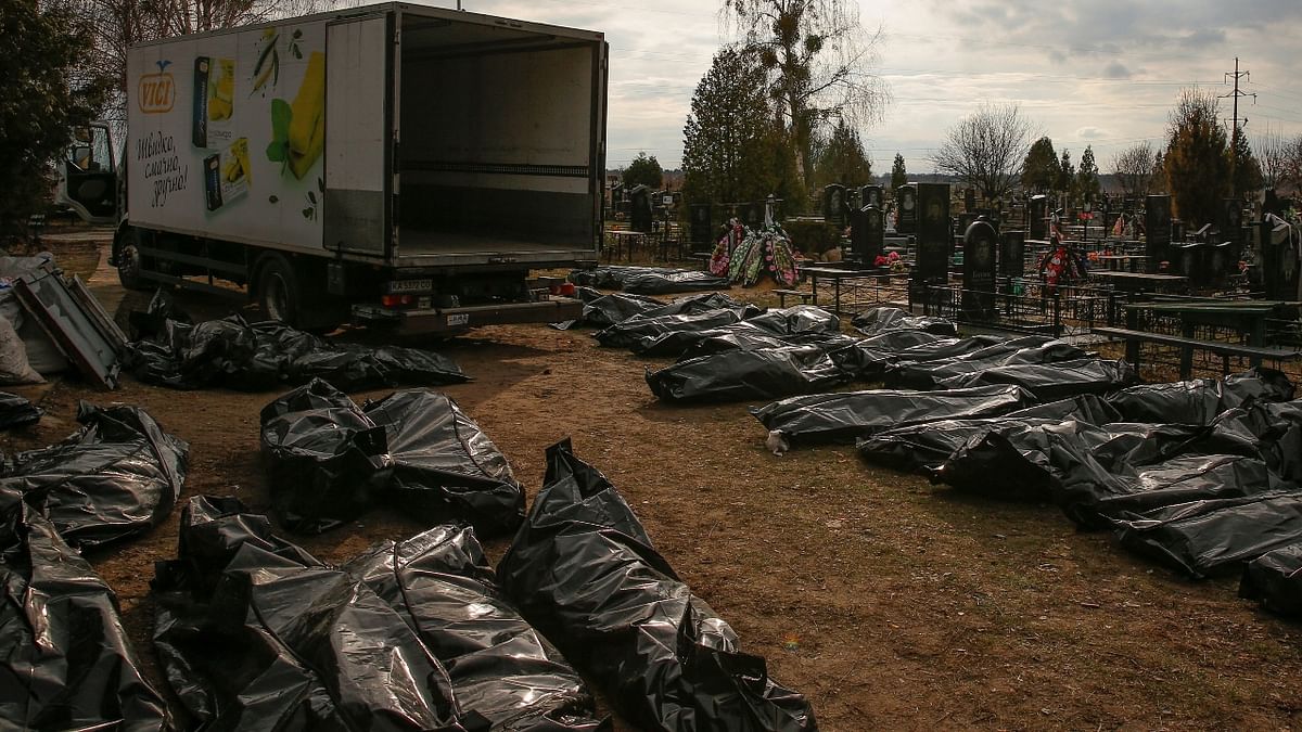 A funeral service employee with bodies of civilians collected from streets in a local cemetery in the town of Bucha, outside Kyiv. Credit: Reuters Photo