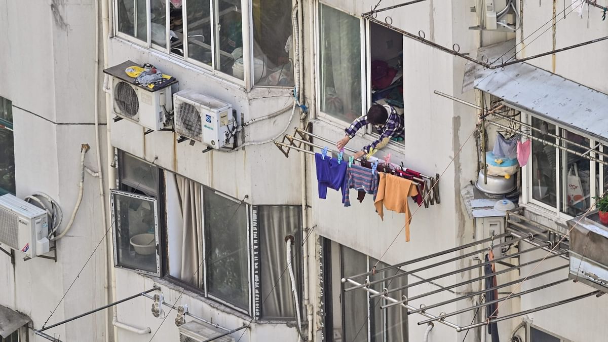 A woman hangs clothes outside her apartment during the second stage of Covid-19 pandemic lockdown in Shanghai. Credit: AFP Photo