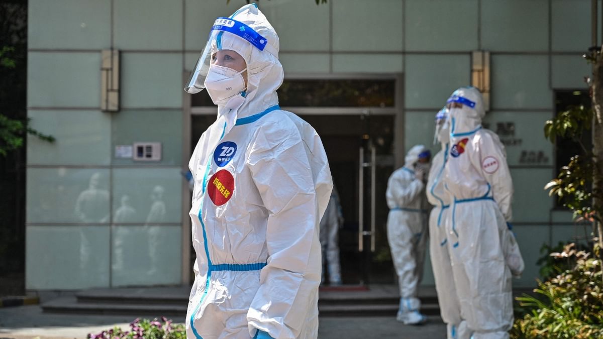 Workers and volunteers wearing PPE kits stand in a compound where residents are being tested for Covid-19 in Jing'an district. Credit: AFP Photo