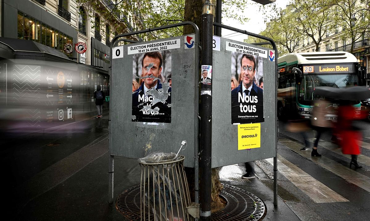 Pedestrians walk past campaign posters of French President and liberal party La Republique en Marche (LREM) candidate for re-election Emmanuel Macron, three days ahed of the first round of the French presidential election, in Paris. Credit: AFP Photo