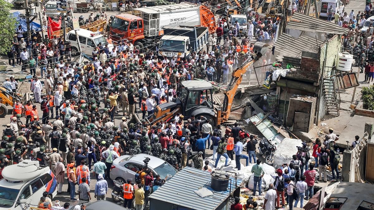 Police officials and members of security forces oversee the demolition of small illegal retail shops by civic authorities in Jahangirpuri, New Delhi. Credit: Reuters Photo