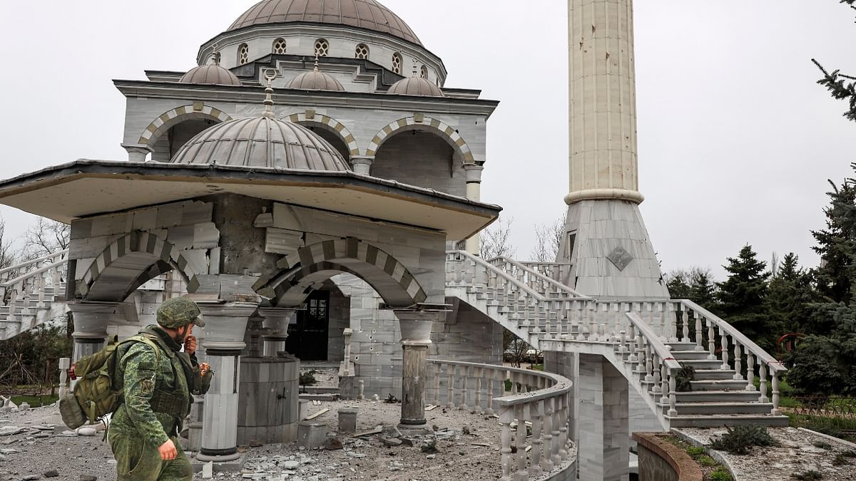A serviceman of Republic militia walks past a damaged mosque in Mariupol, Ukraine. Credit: AP Photo