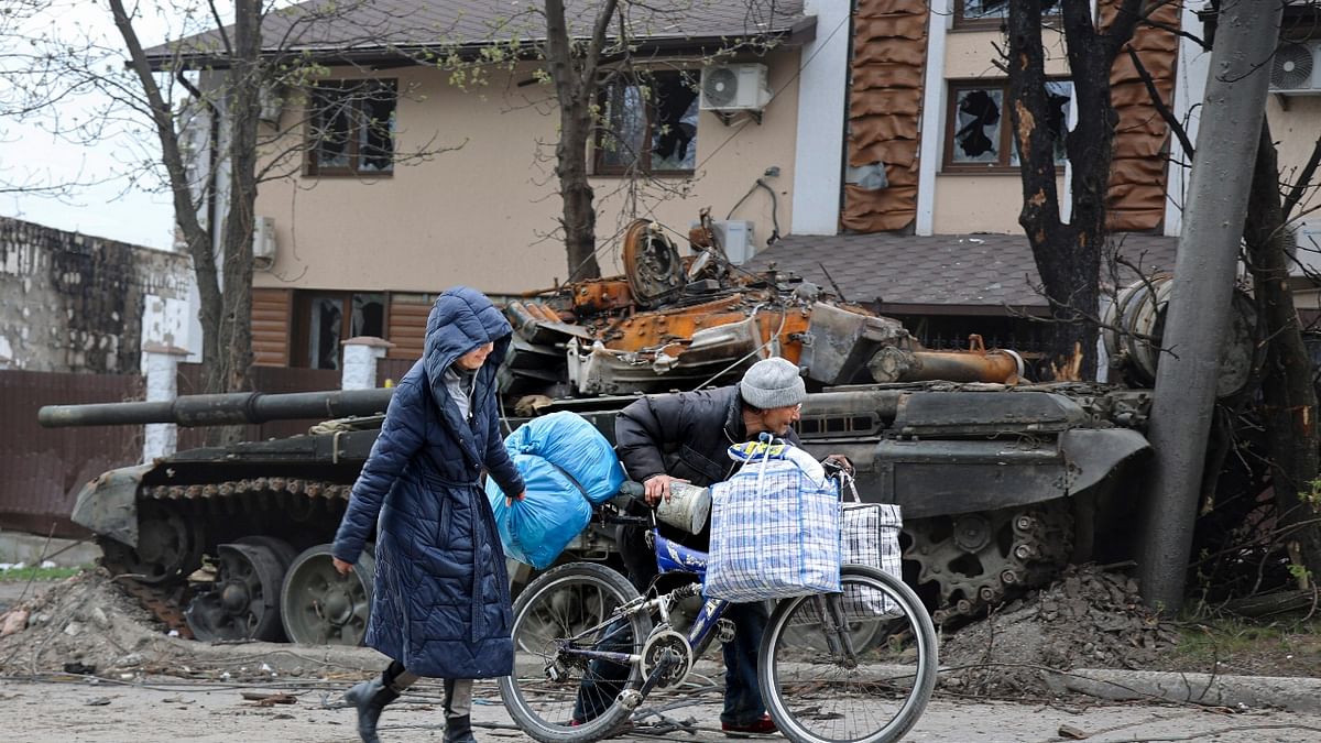 Local civilians walk past a tank destroyed during heavy fighting in an area in Mariupol, Ukraine. Credit: AP Photo