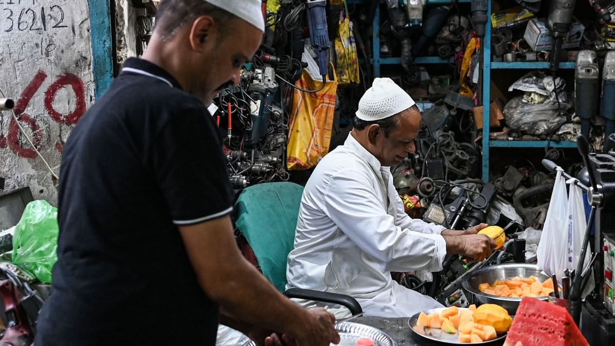 People prepare to break their Iftar fast inside the shops they work at during the Muslim's holy month of Ramadan in New Delhi. Credit: AFP Photo