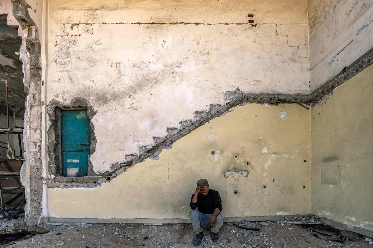 A worker sits in the cleared out remains of a stairwell at a site near the remains of al-Shuruq tower in Gaza City's al-Rimal neighbourhood, which was levelled by Israeli strikes during the 2021 conflict between Hamas and Israel. Credit: AFP Photo