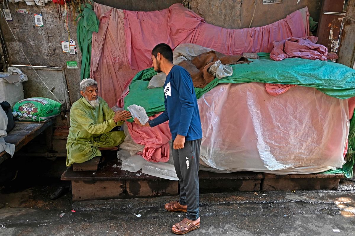 A vendor (L) sells ice to a customer on a hot summer day in an alley in the old quarters of New Delhi. Credit: AFP Photo