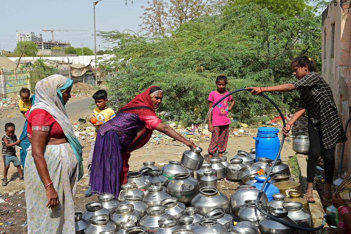 A woman pours drinking water in a pot offered by a temple in the vicinity on a hot summer day on the outskirts of Ahmedabad. Credit: AFP Photo
