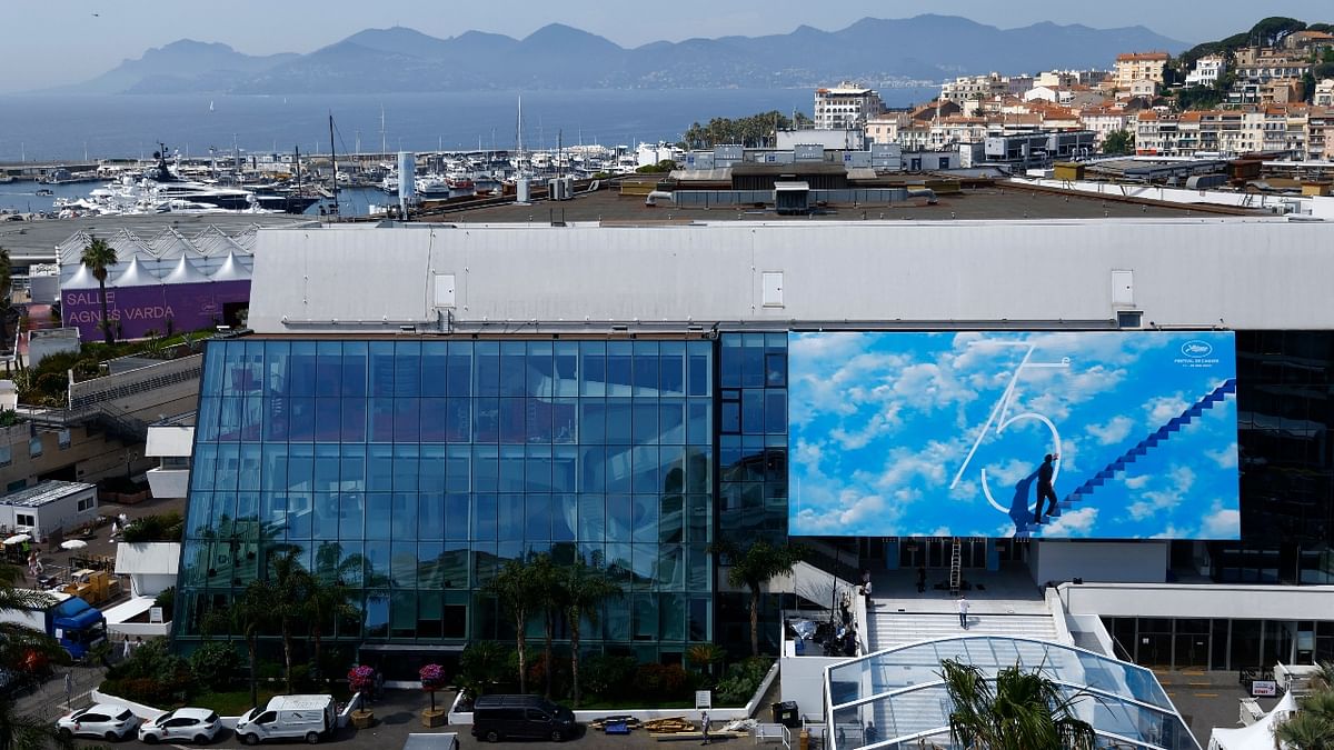 A general view shows the Festival Palace, with a giant canvas of the official poster featuring actor Jim Carrey in the film The Truman Show, and the bay of Cannes as preparations continue on the eve of the opening ceremony of the film festival. Credit: Reuters Photo