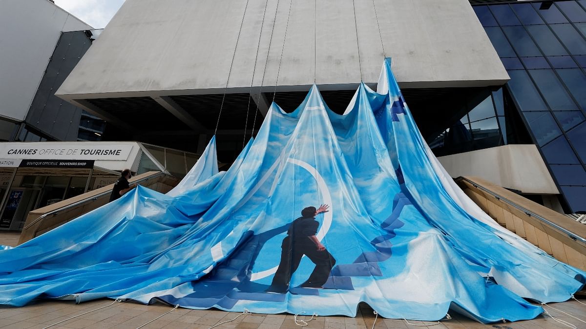 Workers set up a giant canvas of the official poster of the 75th Cannes Film Festival on the facade of the festival palace ahead of the opening ceremony in Cannes, France. Credit: Reuters Photo