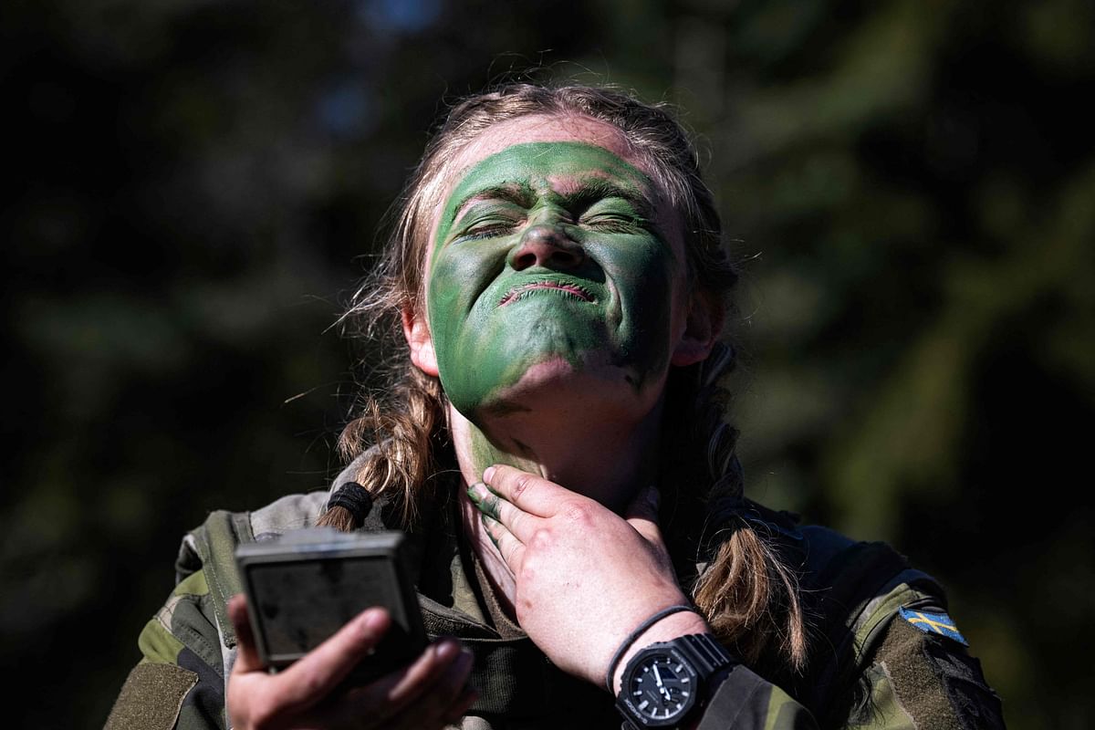 A female soldier of the P18 Gotland Regiment covers her face with paint during a field exercise near Visby on the Swedish island of Gotland. Credit: AFP Photo
