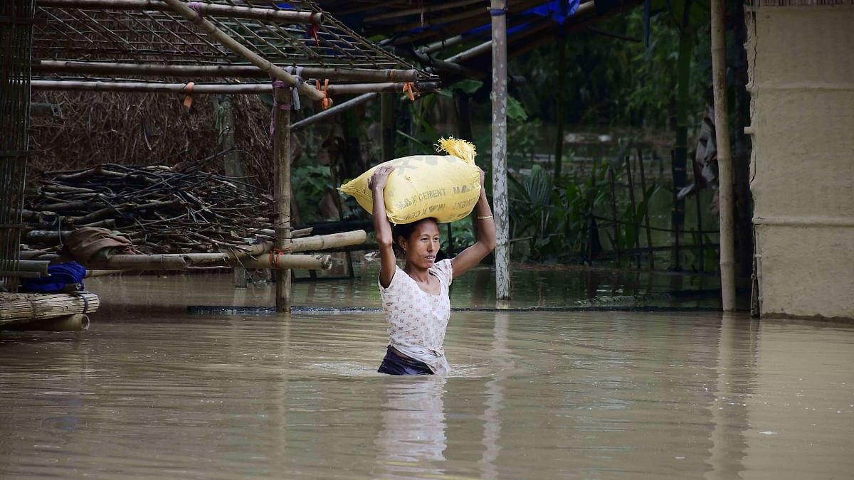 A villager carries her belongings on her head as she wades through a waterlogged area following heavy rainfall at Garukhunda village, in Nagaon, Assam. Credit: PTI Photo