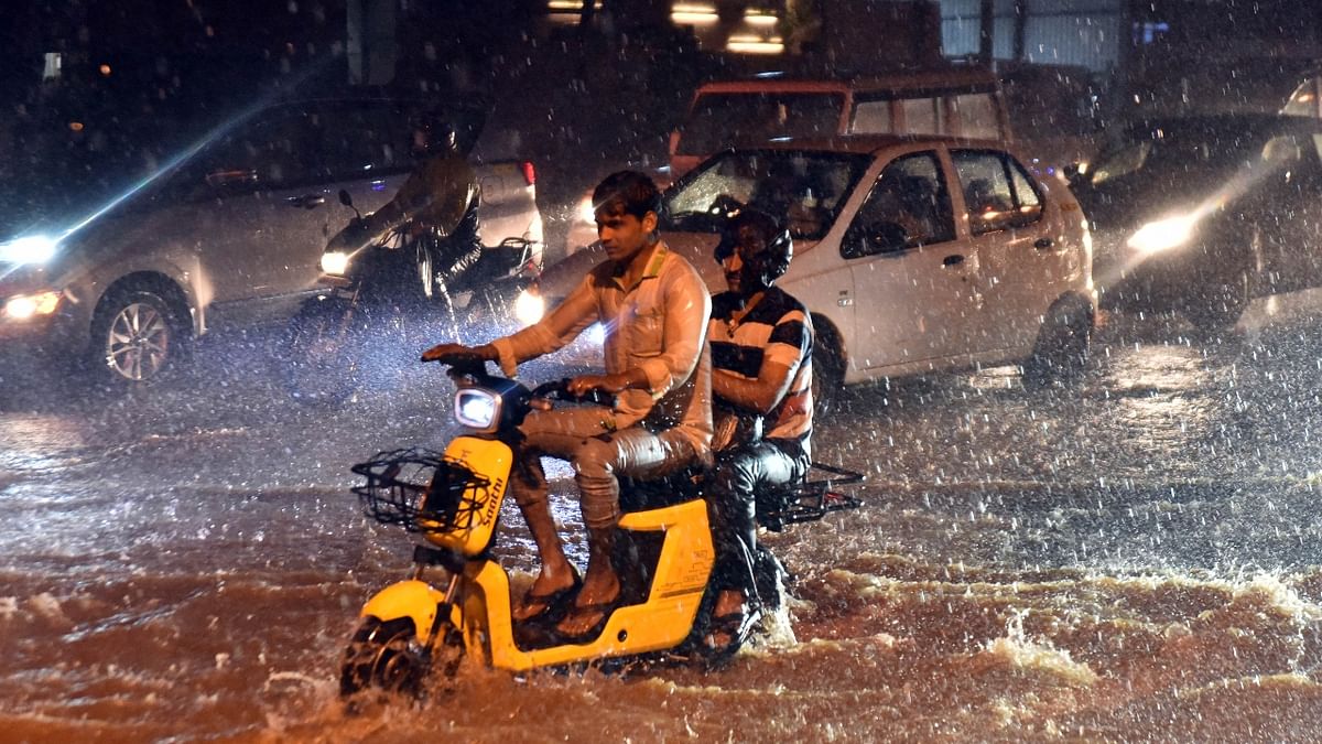 Commuters wade through waterlogged roads as traffic moves at slow pace in Bengaluru. Credit: DH Photo/Anup Ragh T