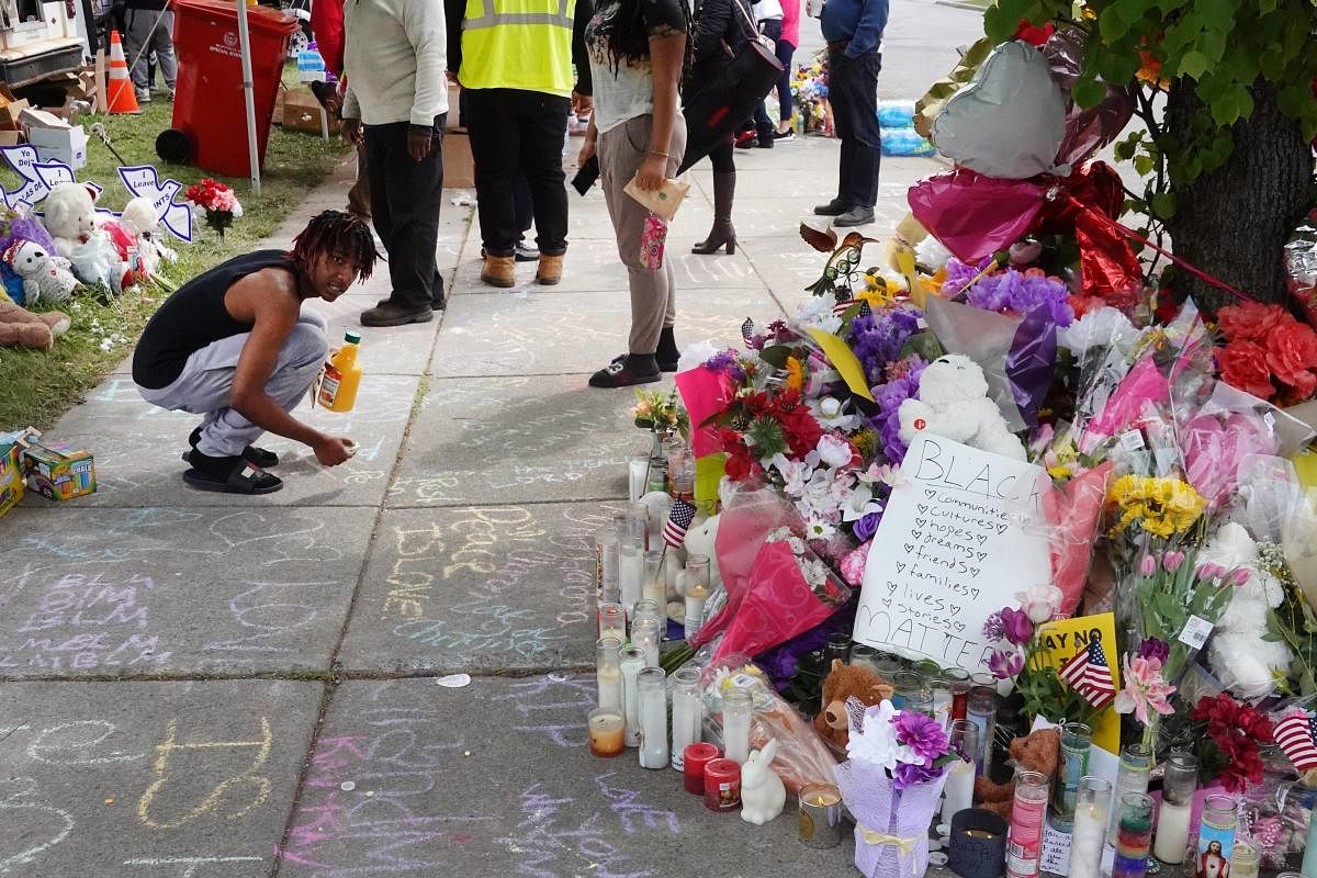 People visit a makeshift memorial set up outside the Tops supermarket in Buffalo, New York. A gunman opened fire at the store on Saturday, killing 10 people and wounding three others. Police say it's being investigated as a racially motivated hate crime. Credit: AFP Photo
