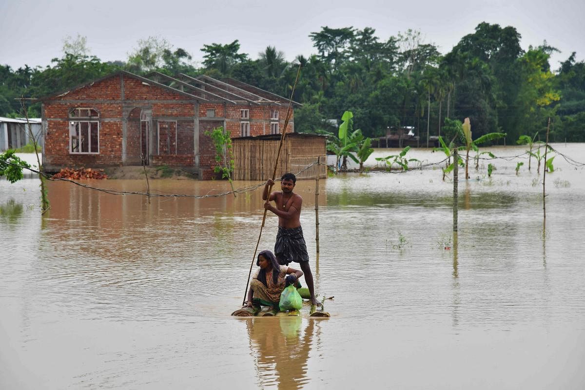Villagers make their way on a raft past homes in a flooded area after heavy rains in Nagaon district, Assam state. Heavy rains have caused widespread flooding in parts of Bangladesh and India, leaving millions stranded and at least 57 dead. Credit: AFP Photo